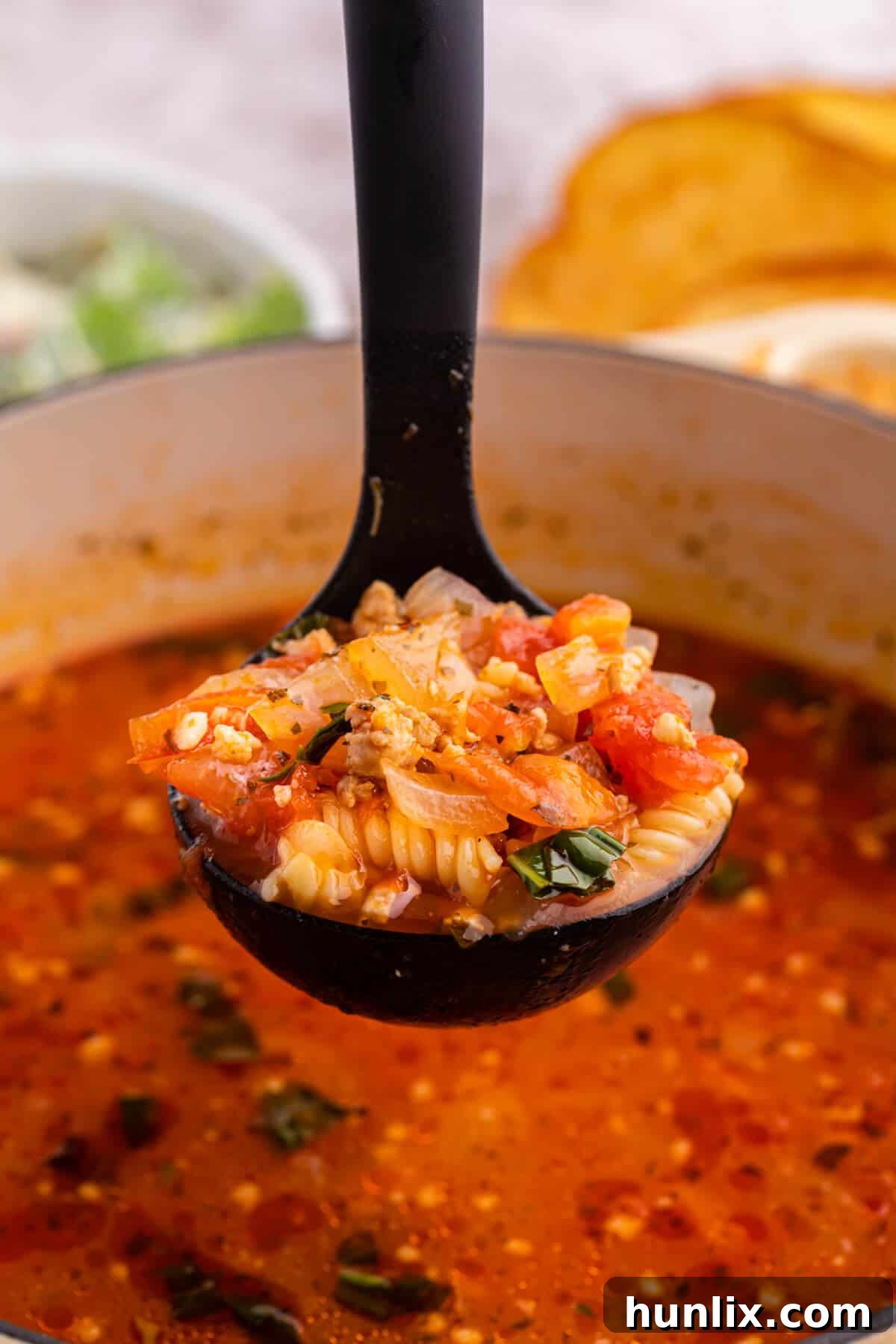 The soup in a ladle over a pot.