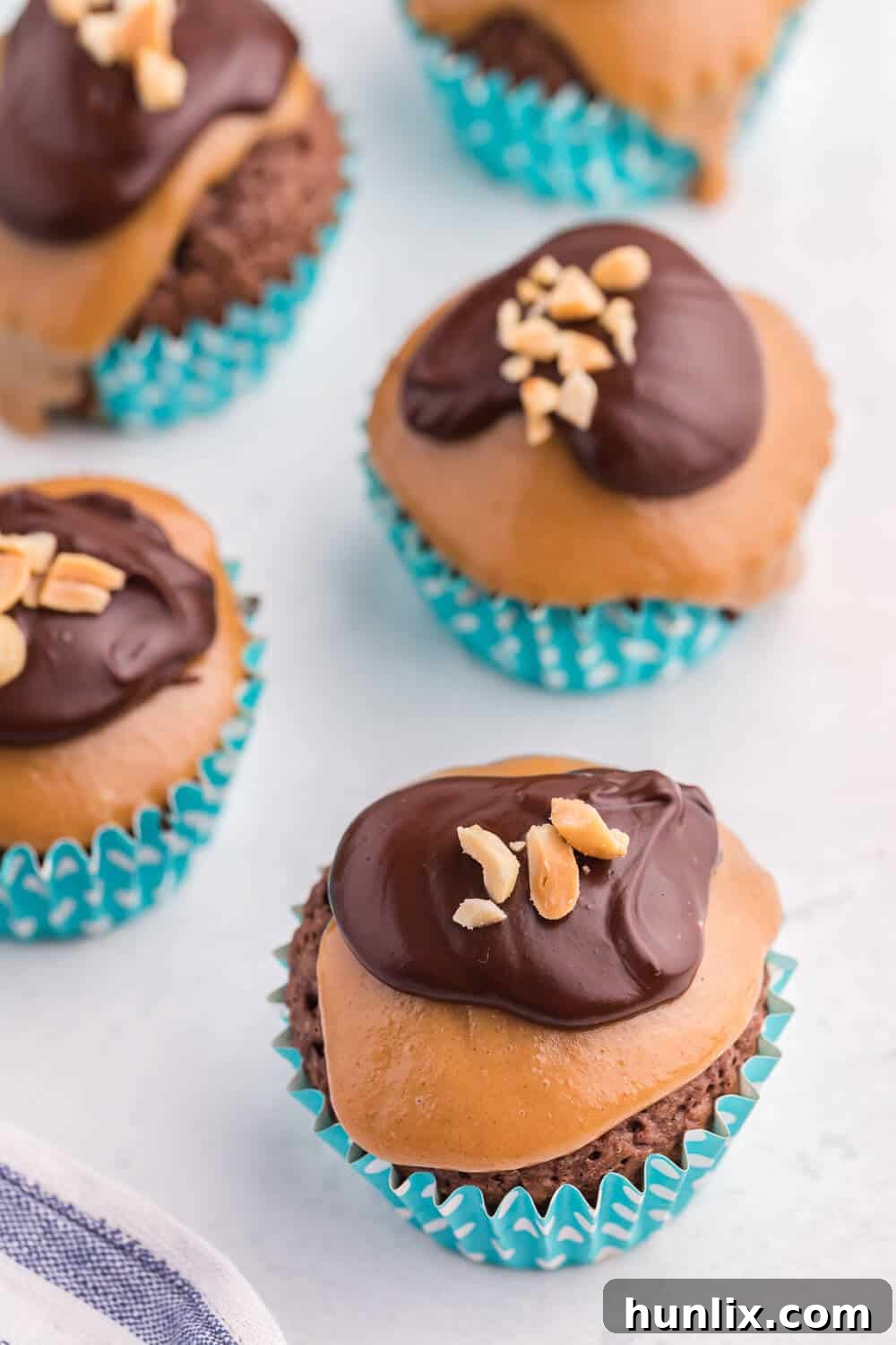 Peanut Butter Brownie Bliss 2 Peanut butter brownie cupcakes on a white board, showcasing their rich toppings.