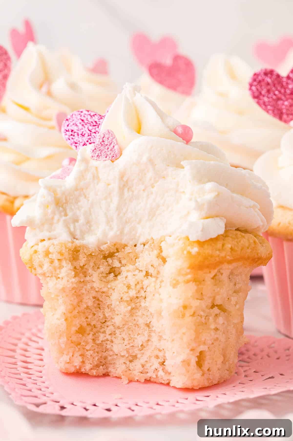 A delicious Valentine's Day cupcake with a bite taken out of it, showcasing its fluffy interior and creamy frosting.