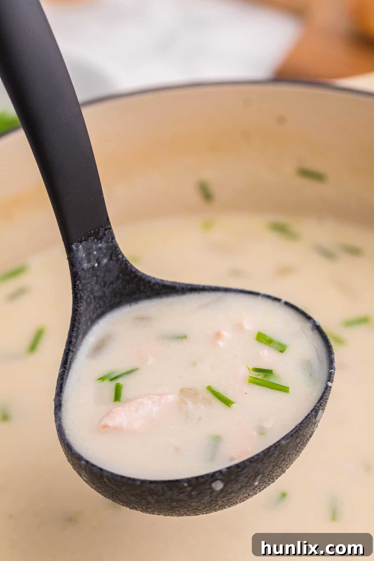 Salmon chowder in a black ladle.