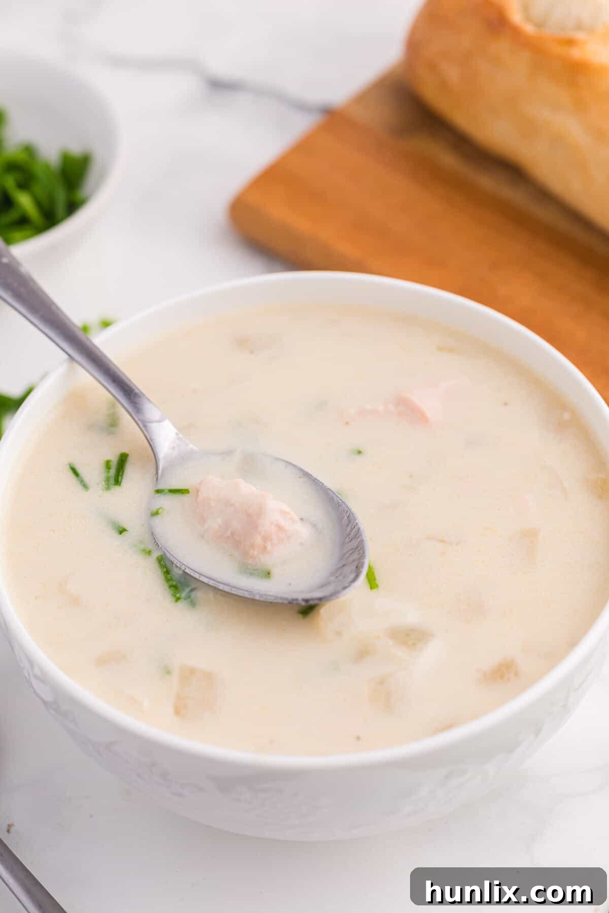 Salmon chowder in a white bowl with a spoon.