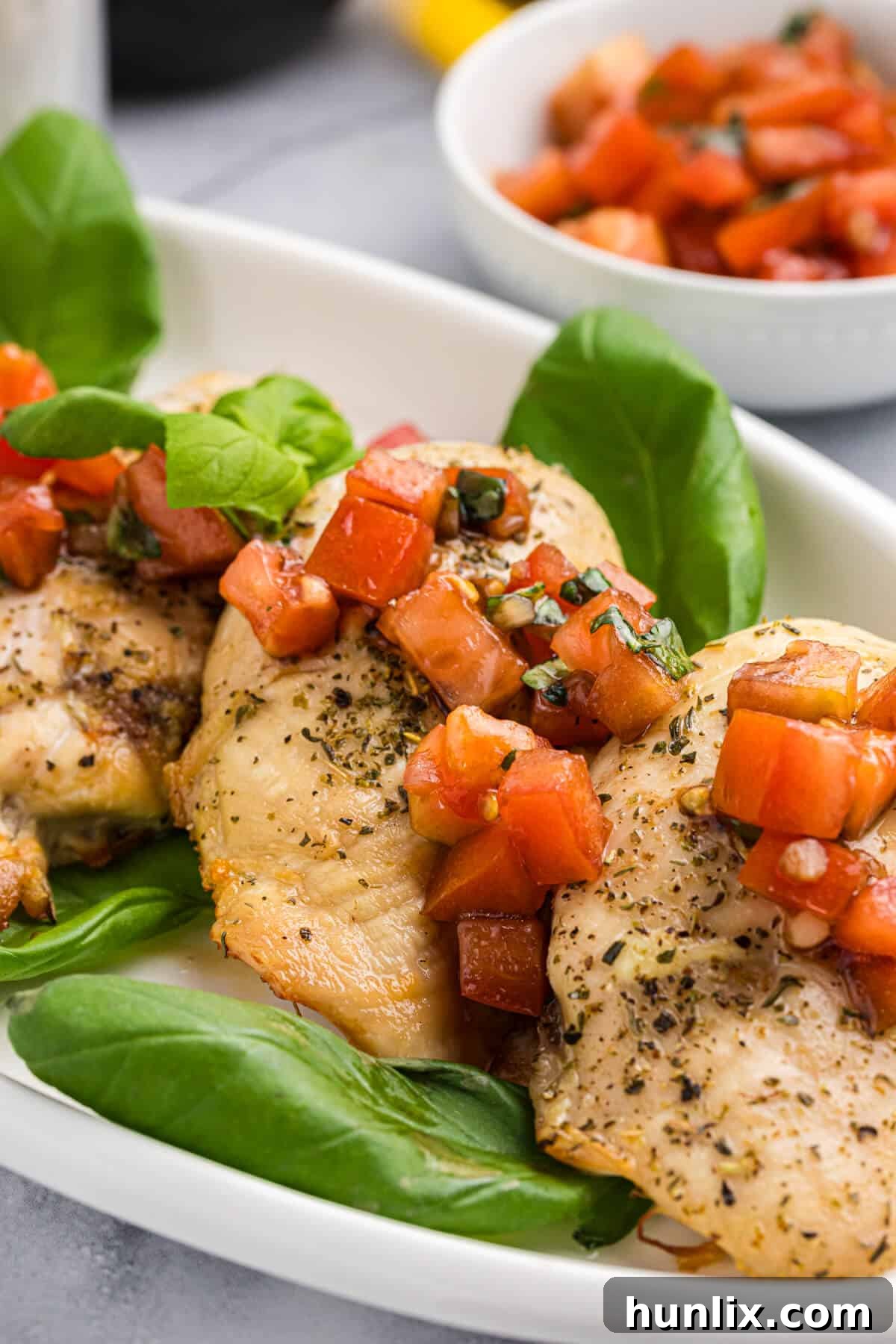 Bruschetta chicken on a platter, ready to be served, garnished with fresh basil.