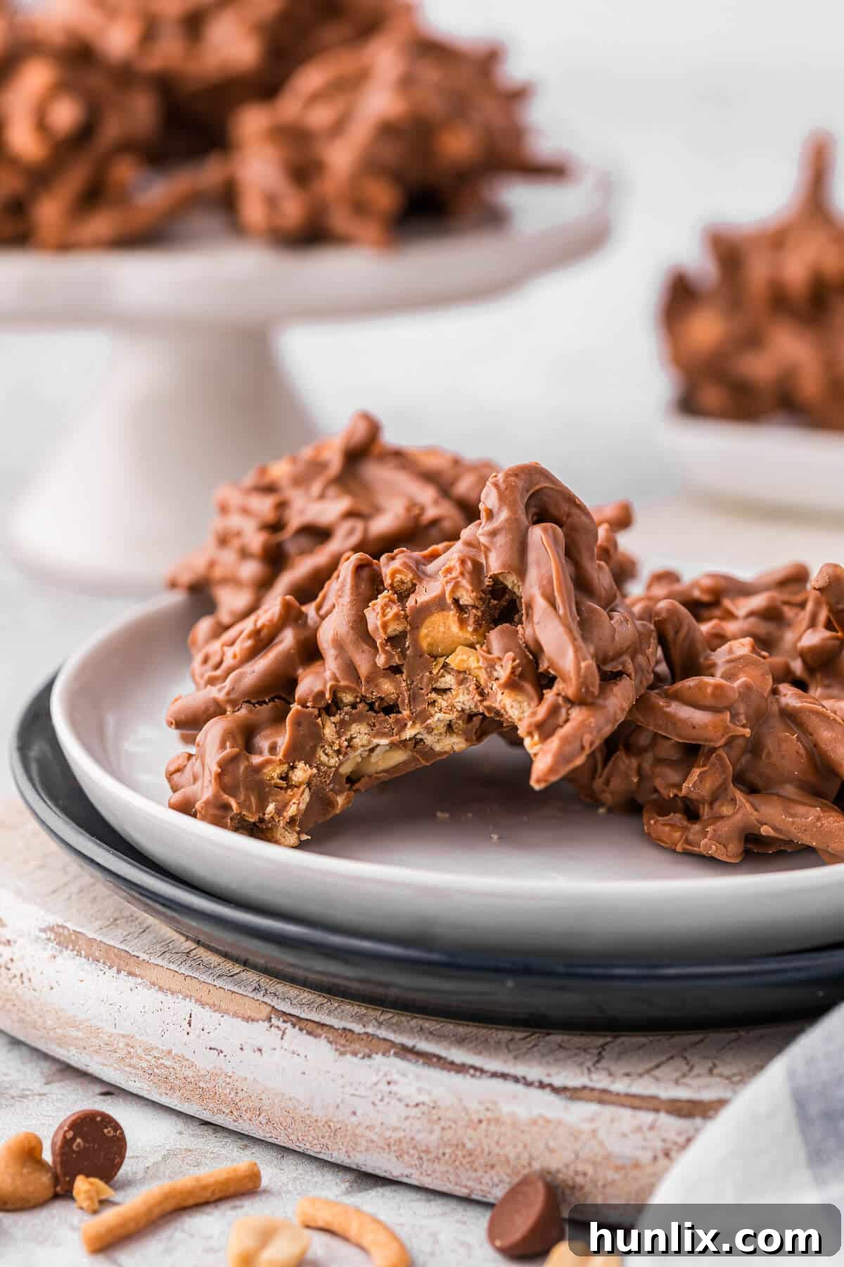 No-Bake Peanut Butter Chocolate Crunch Clusters 6 A beautifully presented plate of No-Bake Chocolate Peanut Butter Haystacks, with one haystack showing a delightful bite taken out of it, revealing its crunchy interior.
