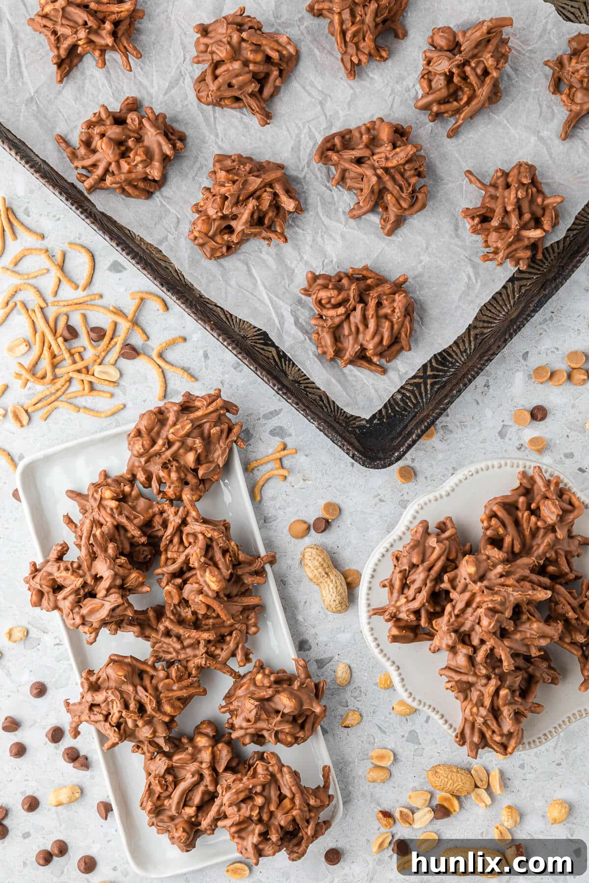 No-Bake Peanut Butter Chocolate Crunch Clusters 9 A diverse collection of No-Bake Chocolate Peanut Butter Haystacks displayed in various settings: on a serving platter, a small plate, and an entire batch on a baking sheet, illustrating their versatility and abundance.