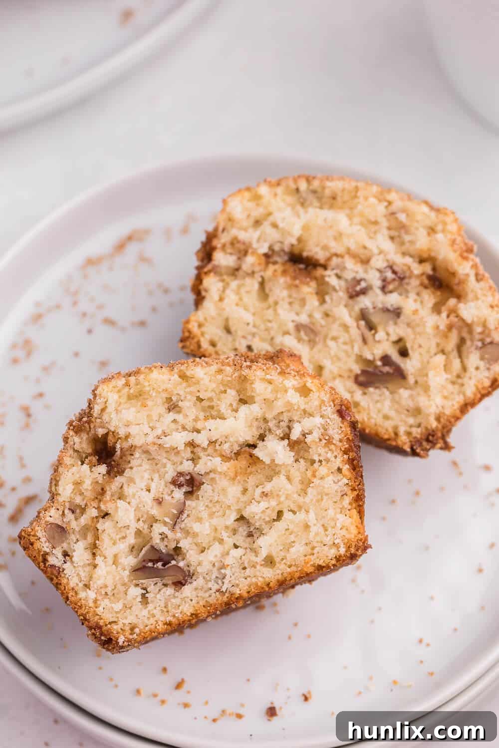 A sliced pecan coffee cake muffin revealing its fluffy texture and pecan pieces