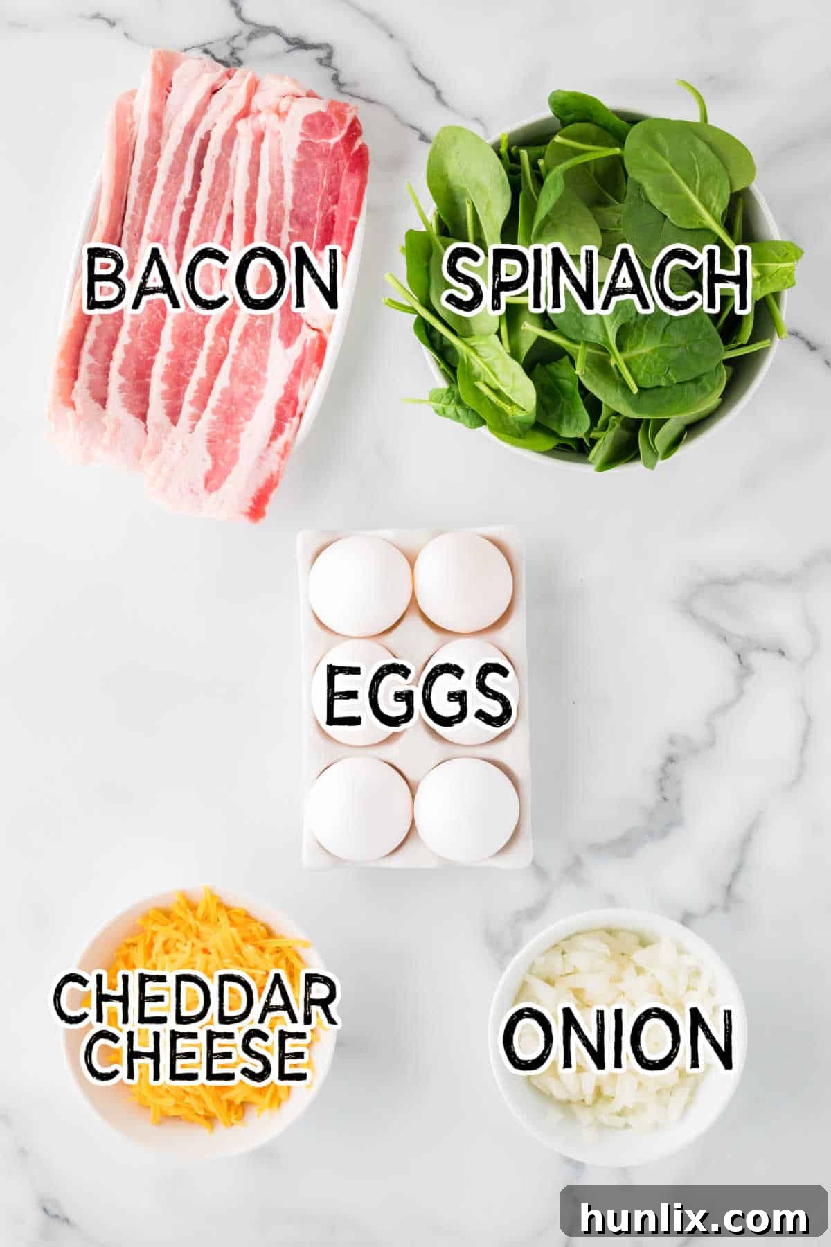 Individual ingredients for spinach and cheese egg muffins laid out neatly on a wooden board, including fresh spinach leaves, shredded cheddar cheese, large eggs, chopped bacon, and diced onion.
