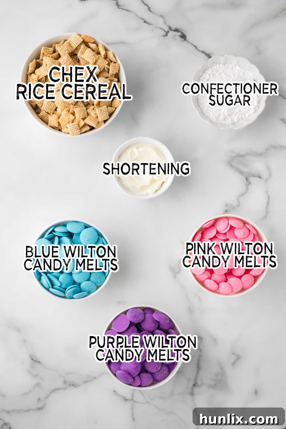 Ingredients for Easter Puppy Chow arranged on a white marble background.